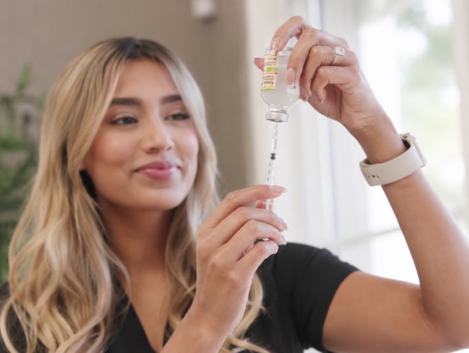 Nurse drawing product from a vial into a syringe